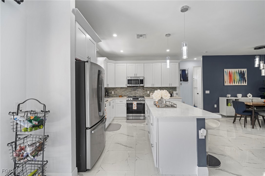 3713 25th Street Southwest Lehigh Acres, FL 33976 - Photo 7 of 31 a kitchen with a refrigerator and a dining table