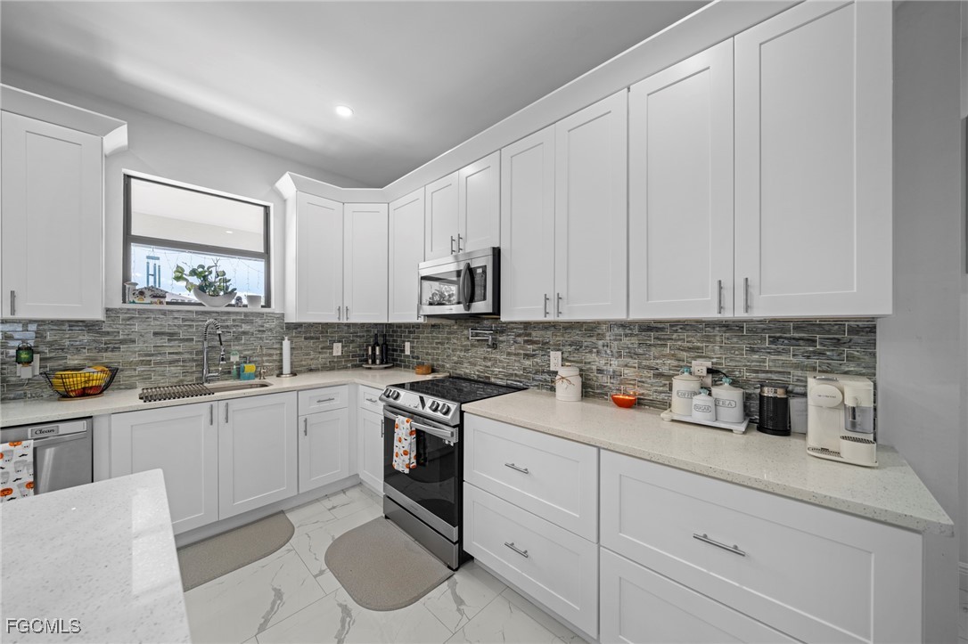 3713 25th Street Southwest Lehigh Acres, FL 33976 - Photo 8 of 31 a kitchen with stainless steel appliances granite countertop a sink stove and cabinets
