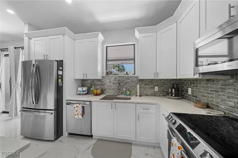 a kitchen with white cabinets and stainless steel appliances