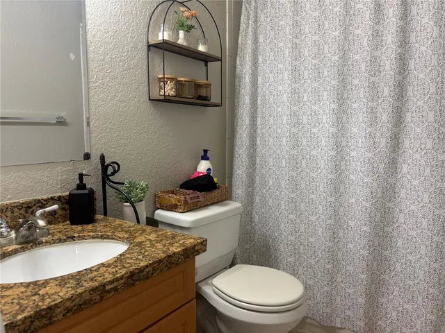 a bathroom with a granite countertop sink and a toilet