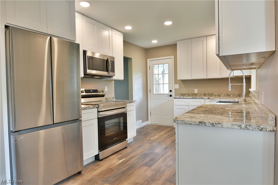 5480 Phillips Rice Road Cortland, OH 44410 - Photo 3 of 35 Kitchen with stainless steel appliances, light hardwood floors, and white cabinetry