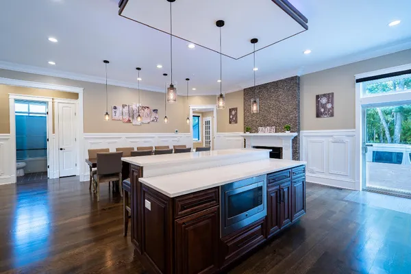 a kitchen with stainless steel appliances kitchen island granite countertop a refrigerator a sink dishwasher and a stove with wooden floor