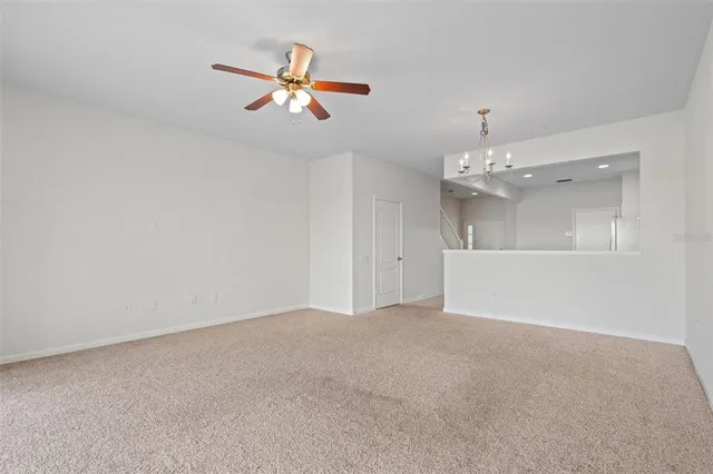 a view of an empty room with a chandelier fan