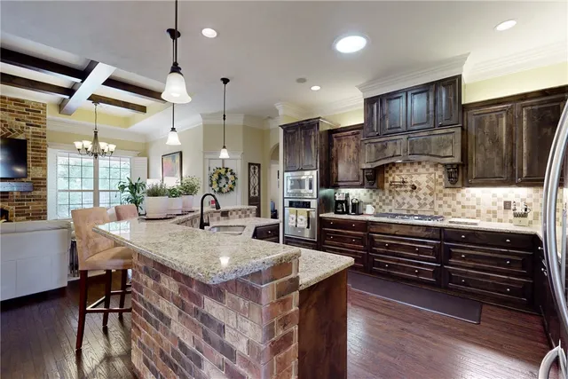 a kitchen with stainless steel appliances kitchen island granite countertop a table chairs and a refrigerator