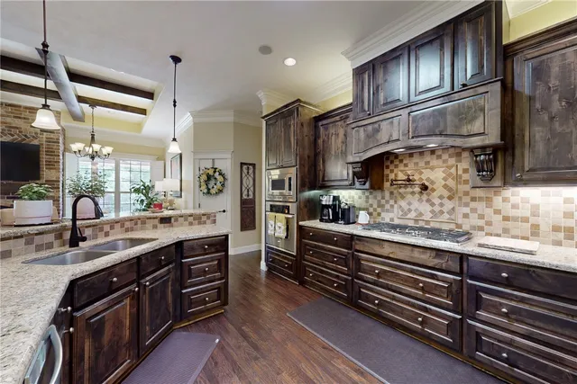 a kitchen with stainless steel appliances granite countertop a sink a stove and a wooden floors