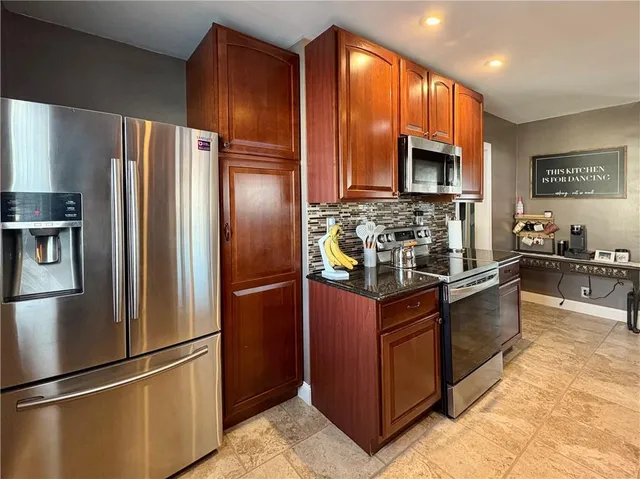 a kitchen with stainless steel appliances granite countertop a refrigerator a stove a sink and a microwave