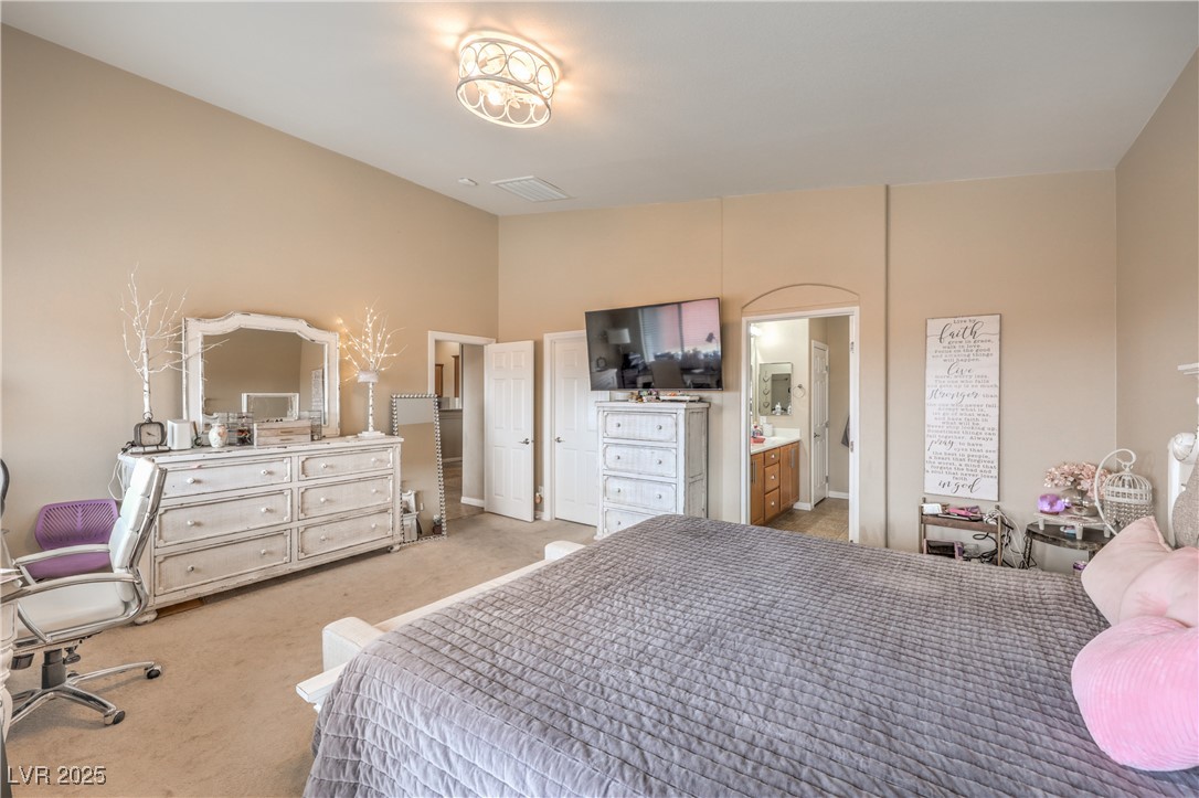 172 Turtle Ridge Avenue Las Vegas, NV 89183 - Photo 19 of 38 Bedroom featuring light carpet, lofted ceiling, and ensuite bath