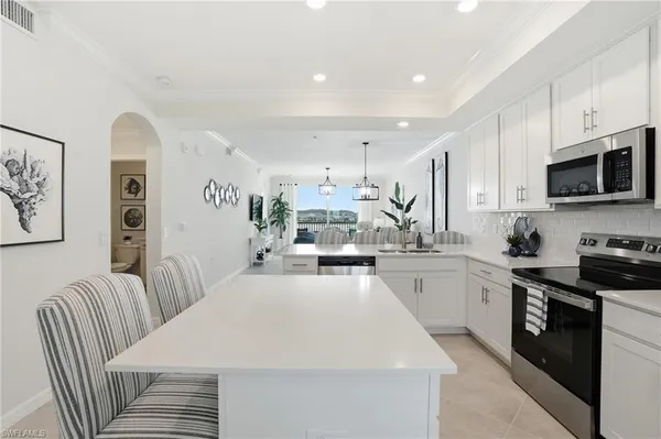 a kitchen with stainless steel appliances a stove a sink a refrigerator a center island and furniture