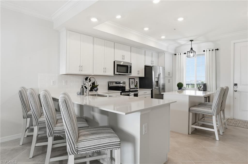 5555 Double Eagle Circle, Unit 3935 Ave Maria, FL 34142 - Photo 10 of 49 a kitchen with a dining table chairs and a refrigerator