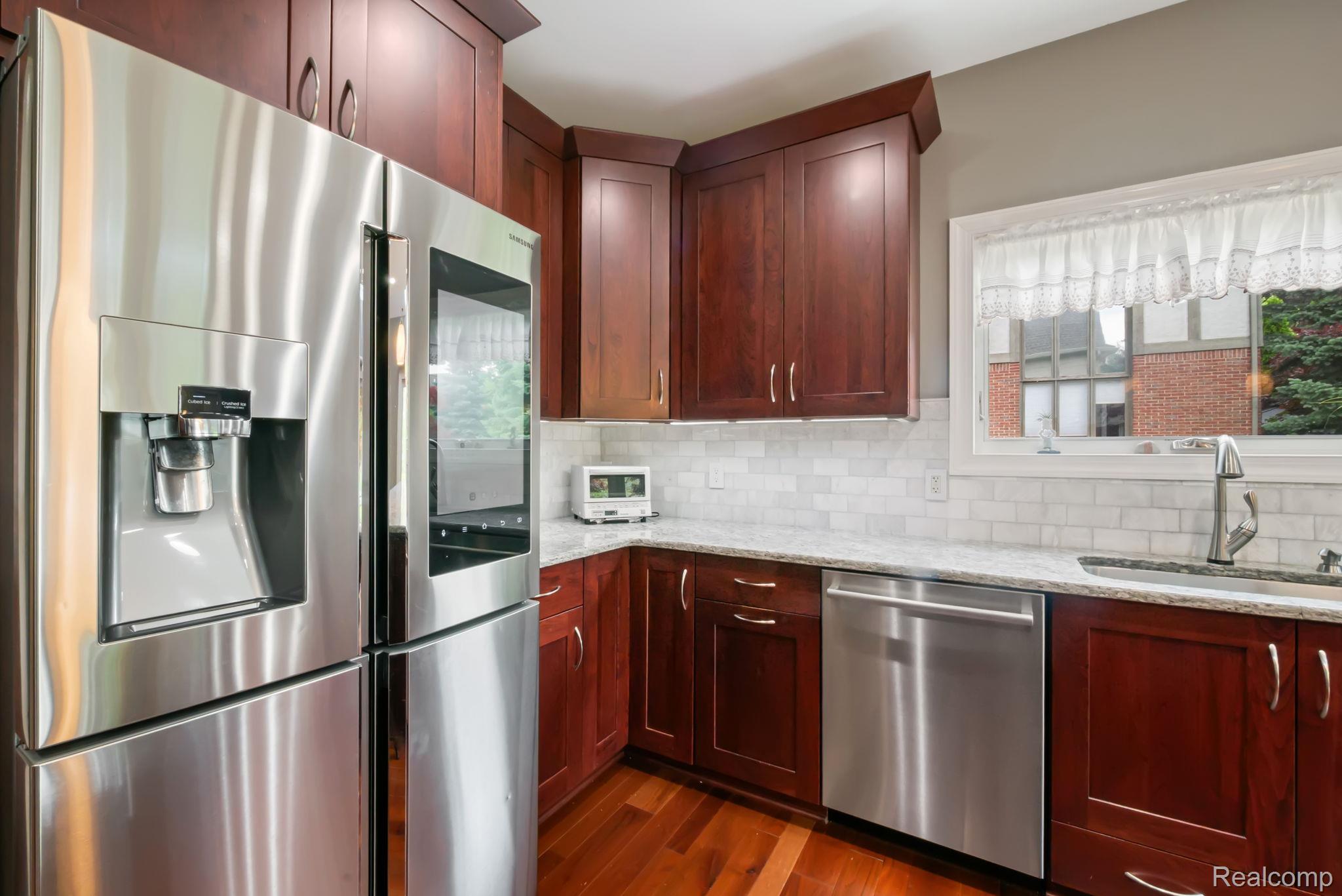 1902 Grayslake Drive Rochester, MI 48306 - Photo 16 of 76 Modern kitchen featuring wood-finish flooring, dark wood cabinetry, and stainless steel appliances including a refrigerator and dishwasher