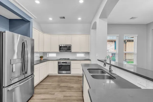 a kitchen with granite countertop a sink stove and refrigerator