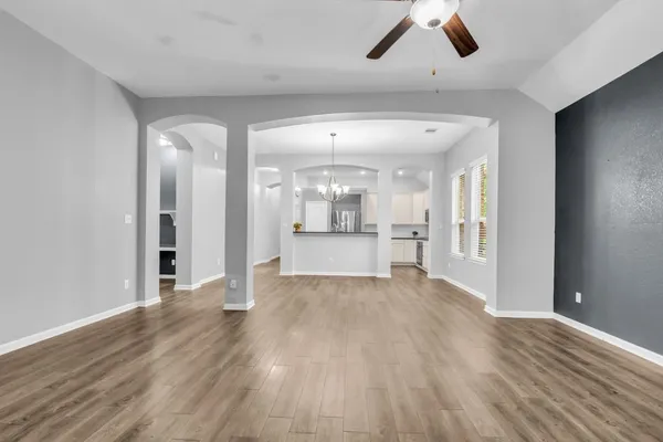 a view of an empty room with wooden floor and a kitchen