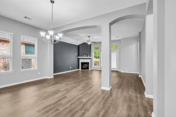 an empty room with wooden floor fireplace and windows