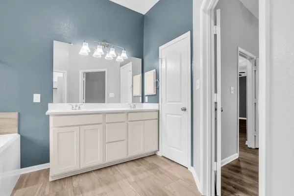 a spacious bathroom with a double vanity sink mirror and bathtub