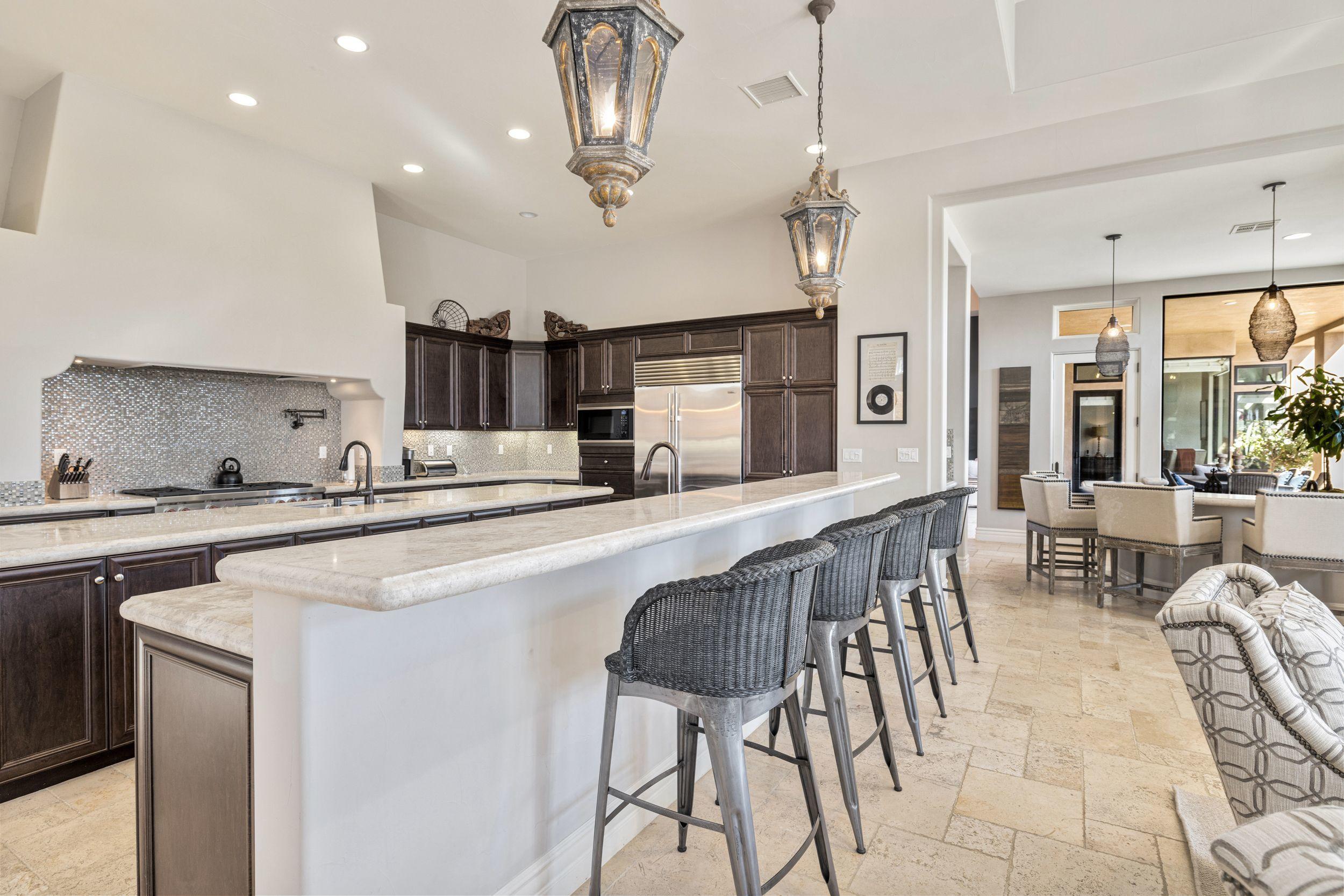 54360 Alysheba Drive La Quinta, CA 92253 - Photo 10 of 24 a kitchen with stainless steel appliances granite countertop a sink a stove a refrigerator cabinets and chairs