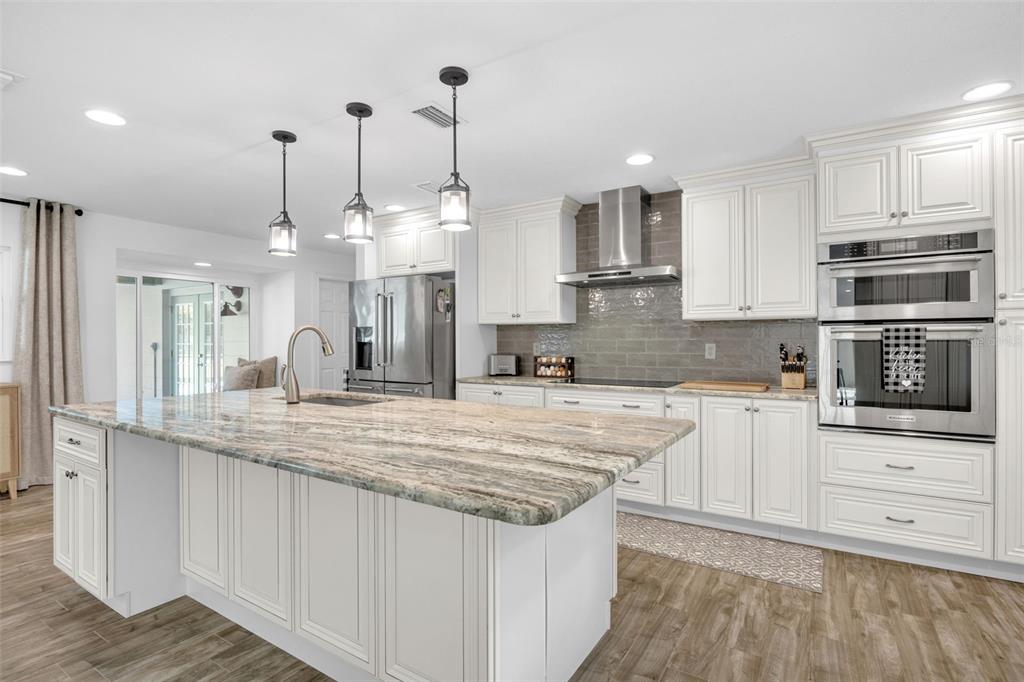 3535 Moores Lake Road Dover, FL 33527 - Photo 10 of 85 The kitchen features a large island with tons of storage and overhead pendant lighting, custom 42" solid wood cabinets, granite countertops, tiled backsplash, matching Kitchen Aid stainless appliances, including a stainless range hood, all new lighting, a large farm sink, and a large wall pantry with pull-out drawers!