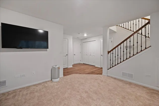 a view of an empty room with wooden floor and a flat screen tv