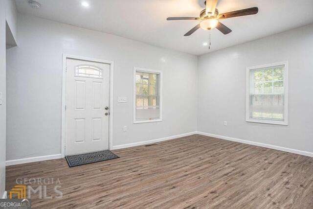 6236 Front Street Douglasville, GA 30134 - Photo 5 of 30 an empty room with wooden floor chandelier fan and windows