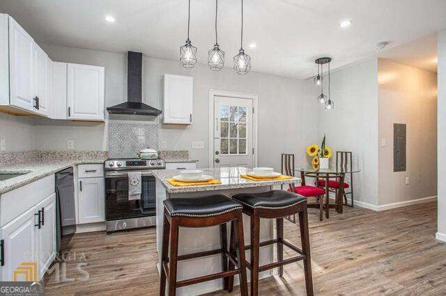 6236 Front Street Douglasville, GA 30134 - Photo 10 of 30 a kitchen with stainless steel appliances kitchen island granite countertop a dining table chairs and white cabinets