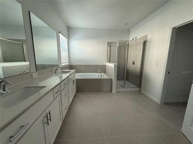 a spacious bathroom with a double vanity sink a mirror and a bathtub