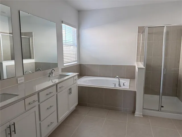 a spacious bathroom with a tub sink and mirror