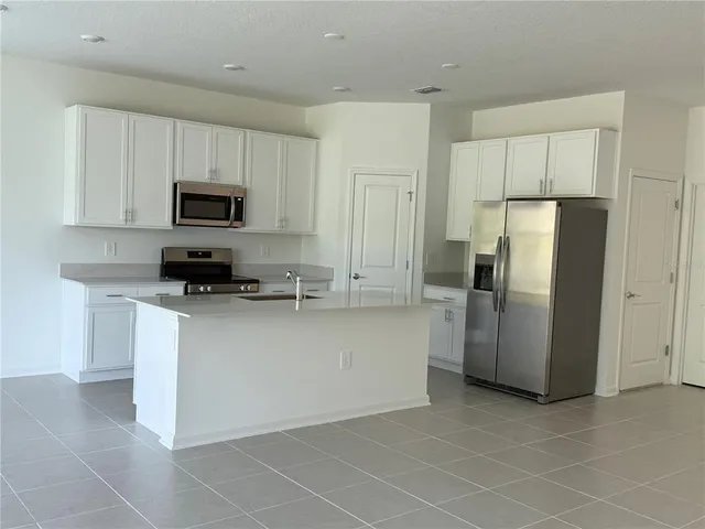 a kitchen with stainless steel appliances a refrigerator a stove a microwave and a sink
