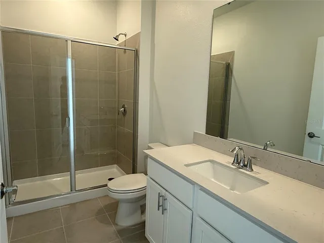 a bathroom with a shower sink vanity mirror and toilet