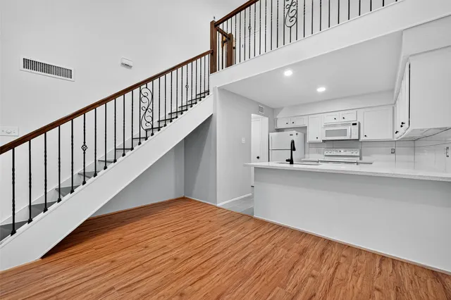 a view of a hallway with wooden floor and staircase