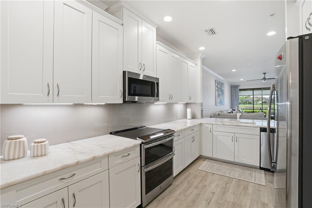 9426 Benvenuto Court, Unit 2104 Naples, FL 34119 - Photo 44 of 45 a kitchen with stainless steel appliances granite countertop a sink dishwasher a stove and a refrigerator with wooden floor