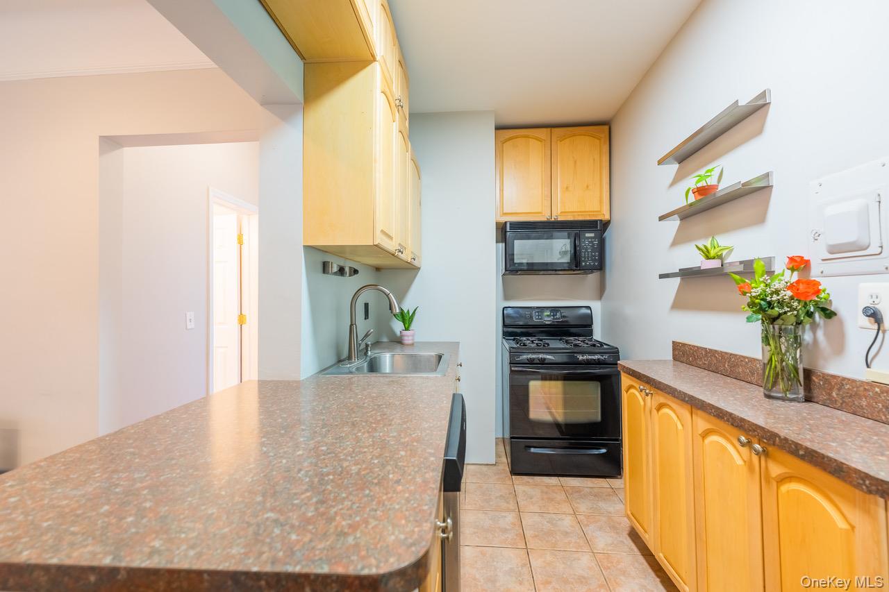4 Maple Drive, Unit 6O Great Neck, NY 11021 - Photo 9 of 28 a kitchen with a stove and a chandelier