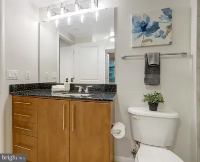 a bathroom with a granite countertop sink mirror and toilet