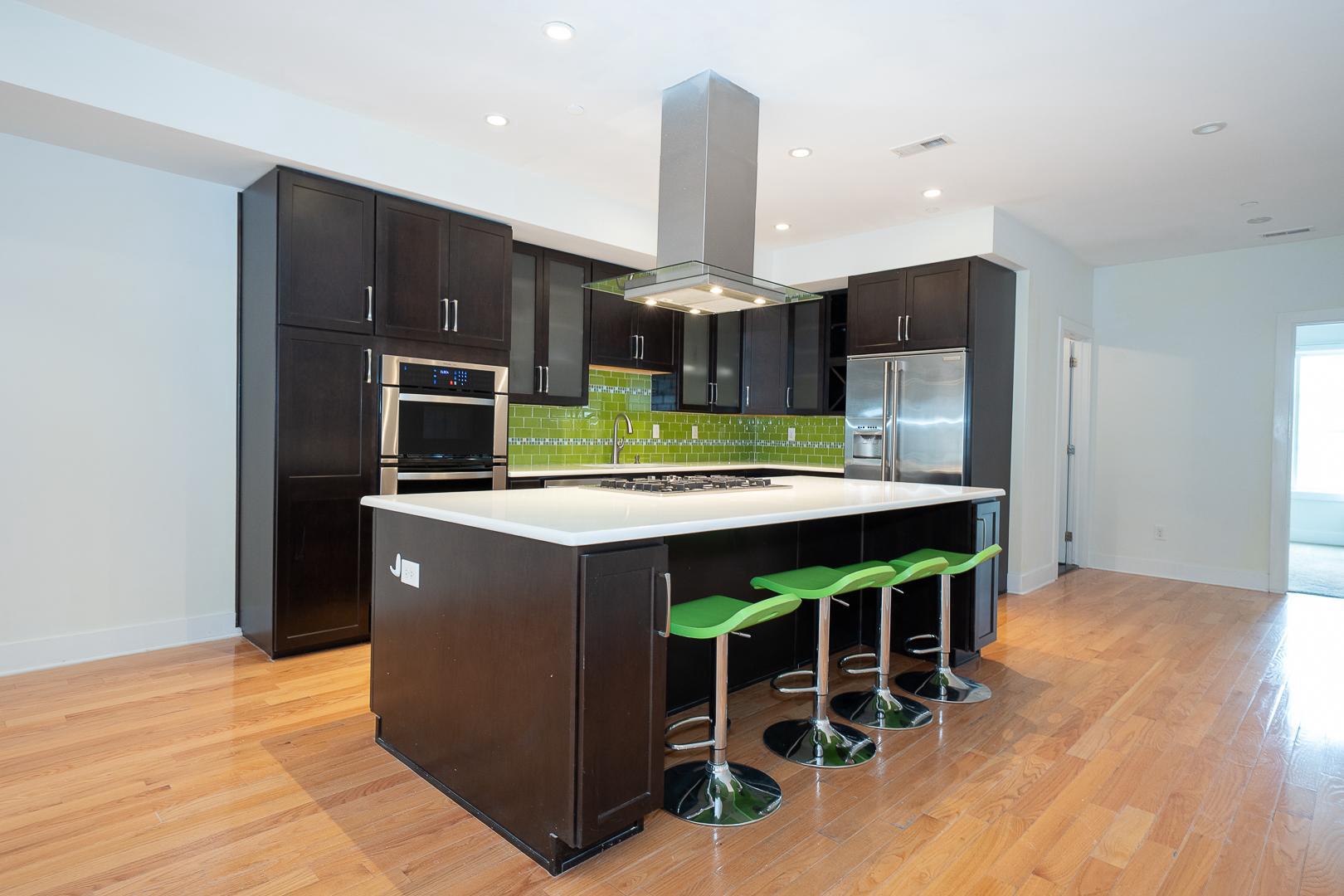 110 Naudain Street, Unit 4 Philadelphia, PA 19147 - Photo 13 of 48 a kitchen with stainless steel appliances kitchen island granite countertop a refrigerator a stove and a wooden floors