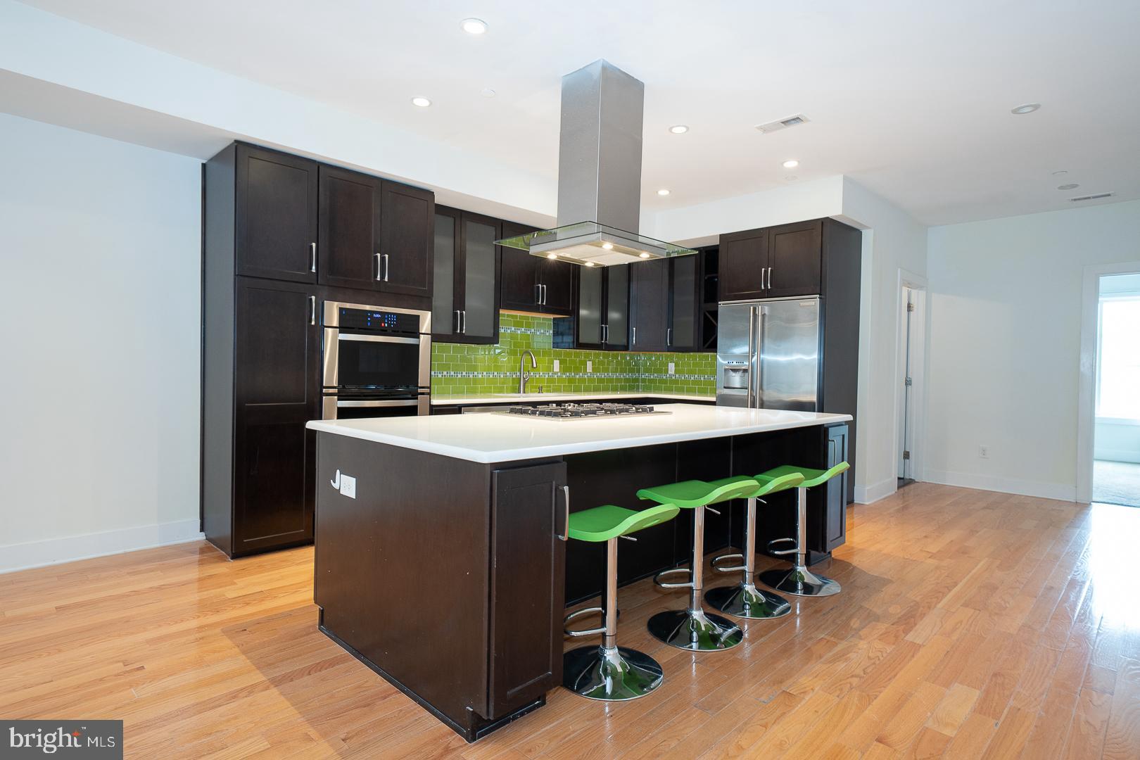 110 Naudain Street, Unit 4 Philadelphia, PA 19147 - Photo 9 of 45 a kitchen with stainless steel appliances kitchen island granite countertop a refrigerator a stove and a wooden floors