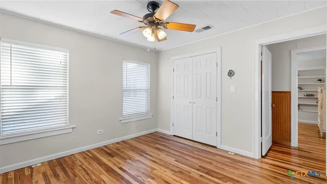 a view of an empty room with window and a chandelier fan