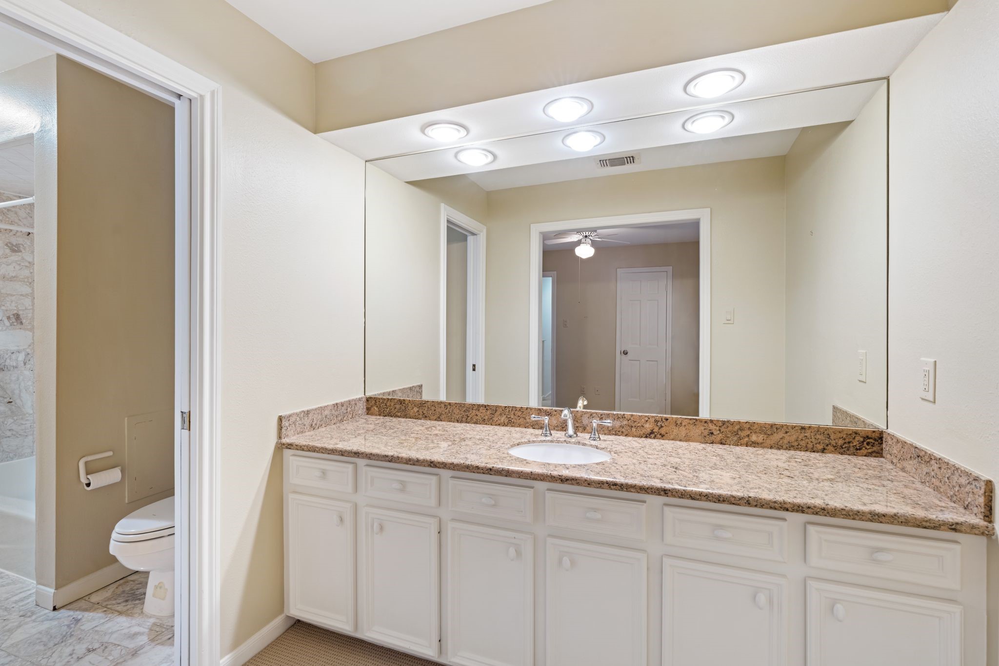 7416 Kelving Street Houston, TX 77030 - Photo 33 of 35 a bathroom with a granite countertop sink a toilet and a mirror