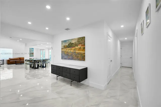 a room with stainless steel appliances lots of white furniture a refrigerator and a sink