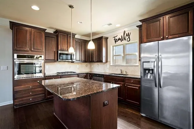 a kitchen with stainless steel appliances granite countertop a refrigerator a stove and a sink