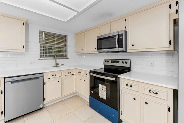 a kitchen with granite countertop white cabinets a sink dishwasher and a stove with wooden floor