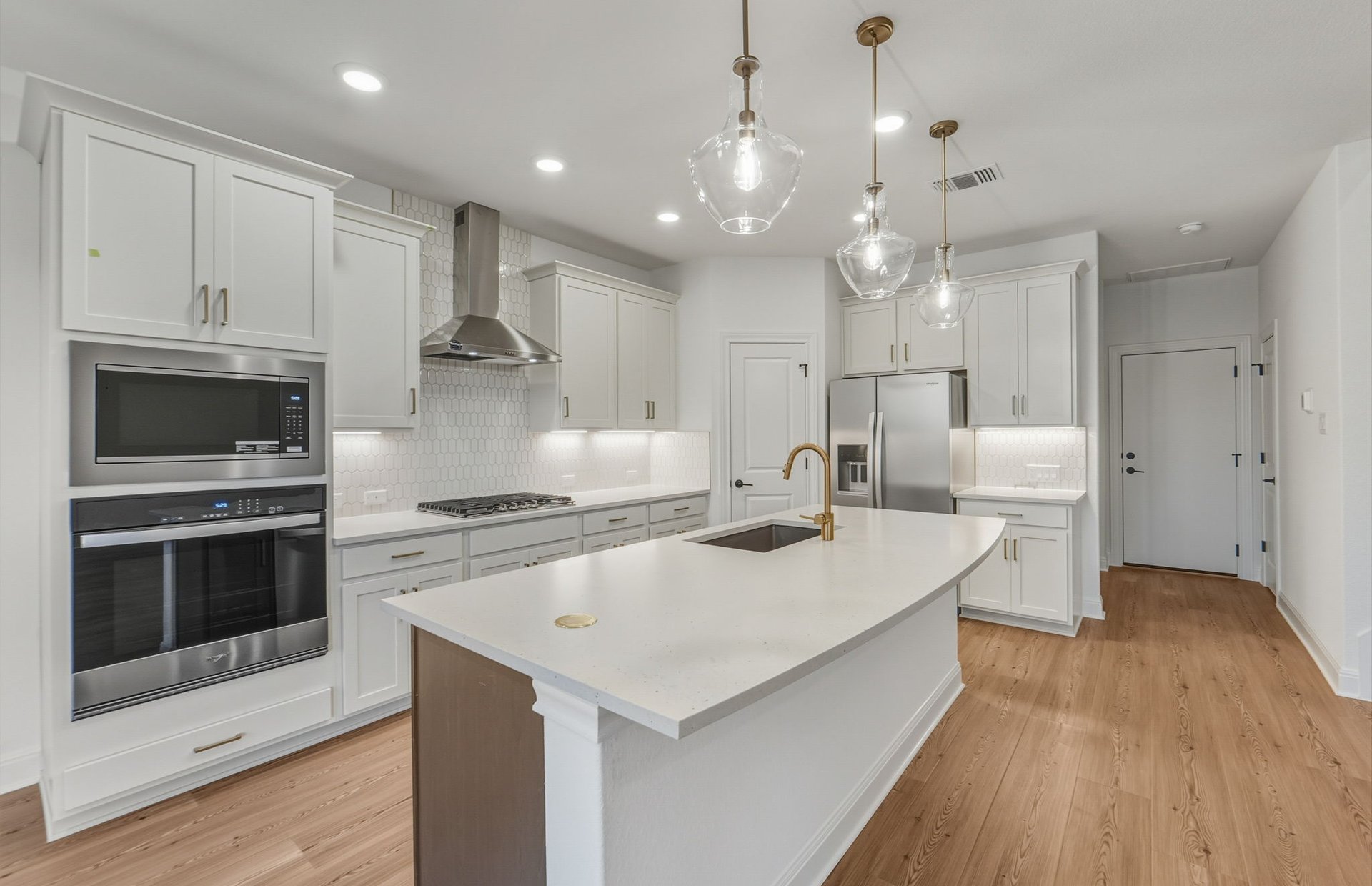 456 Foresail Road Leander, TX 78641 - Photo 5 of 22 a large kitchen with kitchen island a stove a sink a center island and wooden floor