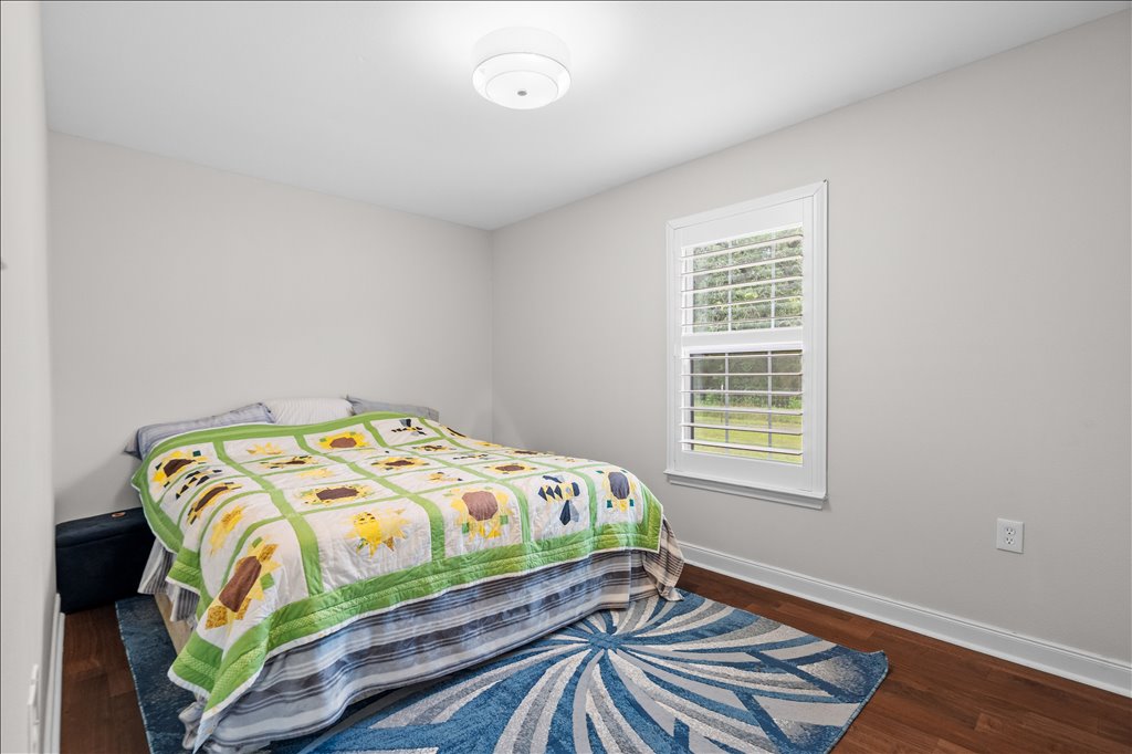608 Whistleville Road Flatonia, TX 78941 - Photo 11 of 26 The secondary bedroom has that same beautiful flooring from the main living area and features another bright window with those matching custom plantation shutters.