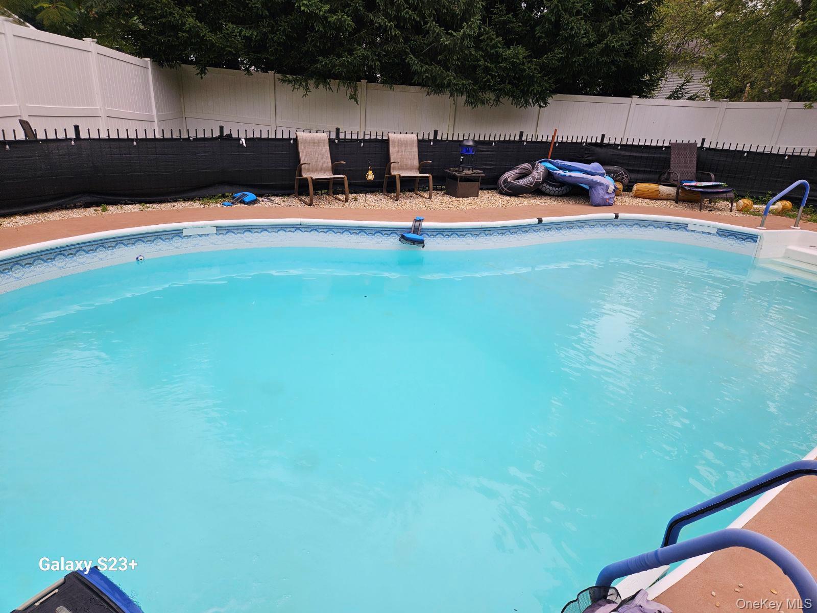 98 Sutton Park Road Poughkeepsie, NY 12603 - Photo 30 of 31 Inviting in-ground pool with integrated steps, surrounded by a painted concrete deck and a white privacy fence