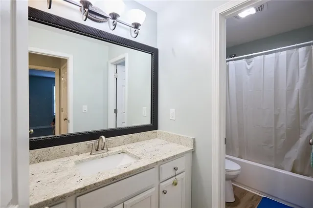 a bathroom with a granite countertop sink toilet and shower