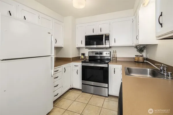 a kitchen with stainless steel appliances a refrigerator sink and white cabinets