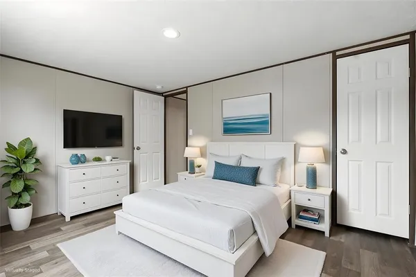 a bedroom with a large bed and a flat tv screen on dresser