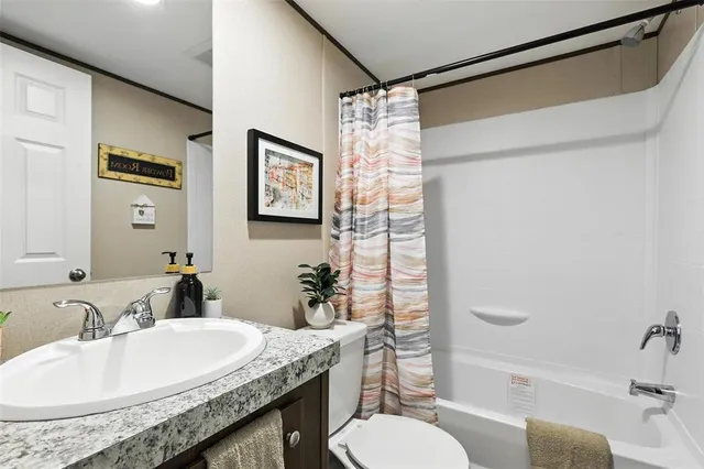 a bathroom with a granite countertop sink toilet a mirror a vanity and shower