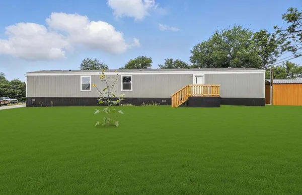 a view of a white house with a big yard and sitting area