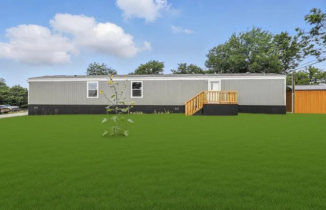 a view of a white house with a big yard and sitting area