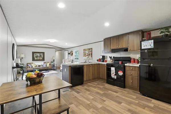 a kitchen with stainless steel appliances kitchen island granite countertop a refrigerator stove top oven and sink