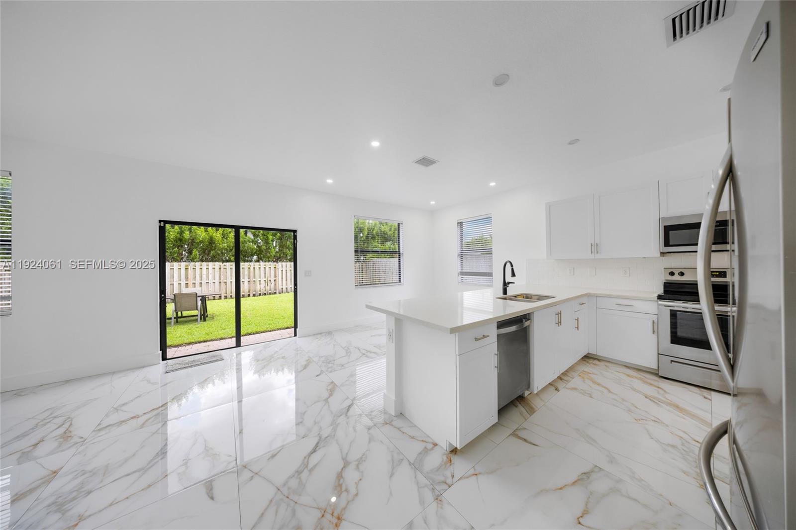 268 Northeast 210th Way Miami, FL 33179 - Photo 13 of 98 a large white kitchen with granite countertop a large window and a sink