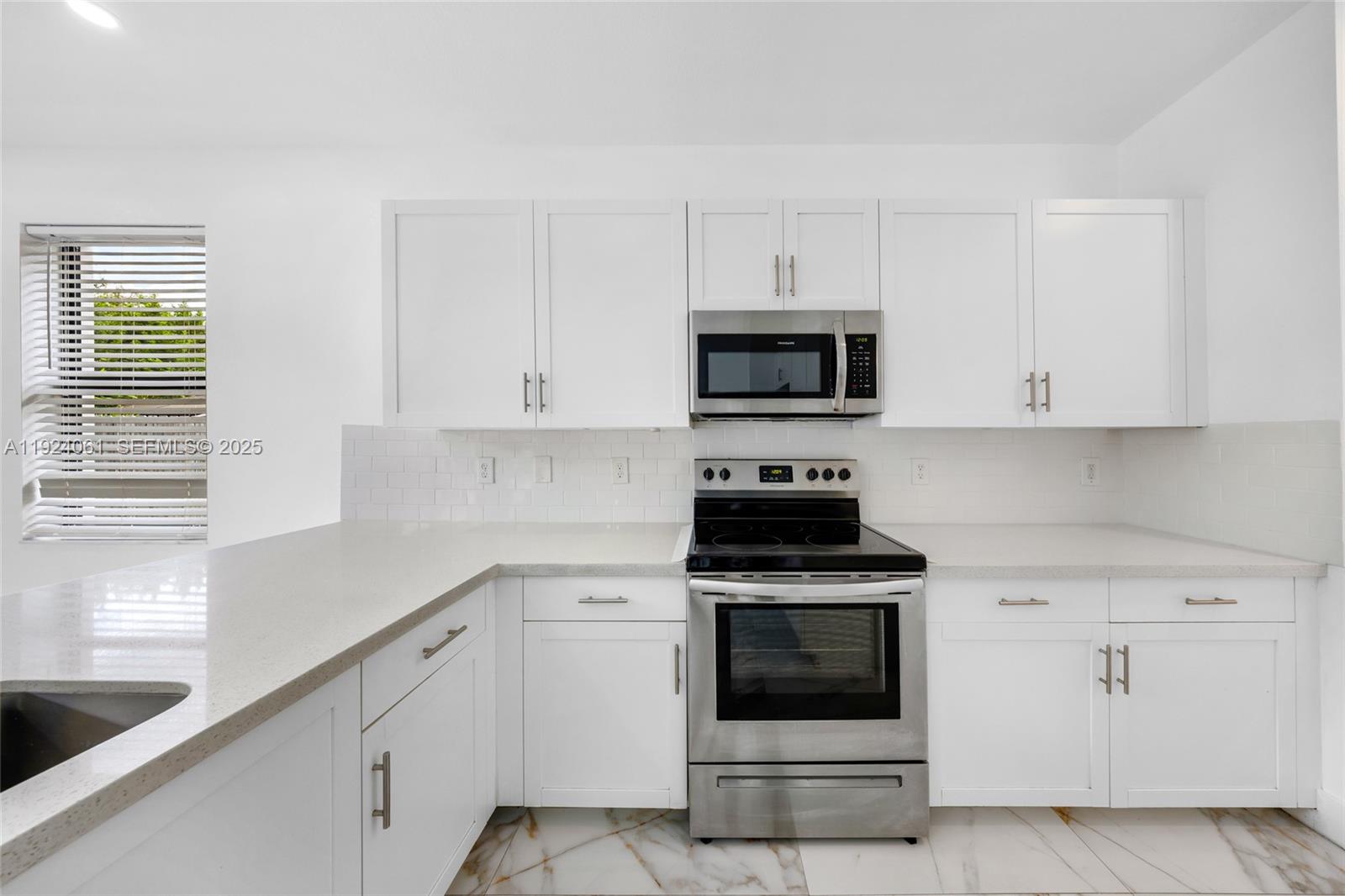 268 Northeast 210th Way Miami, FL 33179 - Photo 15 of 98 a kitchen with white cabinets and stainless steel appliances